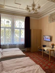 a bedroom with two beds and a table and windows at Hotel Gunia in Berlin