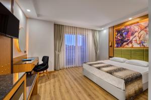 een hotelkamer met een bed, een bureau en een televisie bij Sealife Buket Resort & Beach Hotel - Ultra All Inclusive in Okurcalar