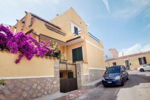 a car parked in front of a house with purple flowers at I Viaggi di Ki in Santa Teresa Gallura