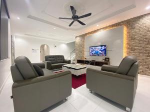 a living room with couches and a flat screen tv at Langkawi Cozy Holiday Home at Taman Seri Aman by Zervin in Kuah