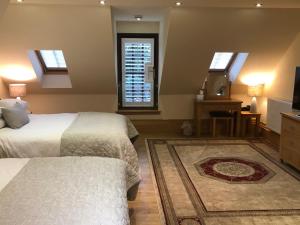 a bedroom with two beds and a television and windows at Roslin Self Catering in Roslin