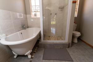 ein Bad mit einer Badewanne, einer Dusche und einem WC in der Unterkunft Misty Morn Cottages in Muldersdrift
