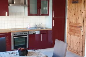 a kitchen with red cabinets and a table with a bag on it at 2 Ferienhaus Andermichlhof in Geltendorf +12 photos