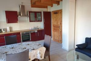 a kitchen with red cabinets and a table with chairs at 2 Ferienhaus Andermichlhof in Geltendorf
