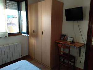 a bedroom with a cabinet and a desk with a television at Pension zelaigane in Mendexa