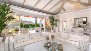 Elle comprend un salon doté d'un mobilier blanc et d'un lustre. dans l'établissement Eden Park Luxury Villas, à Sunny Beach