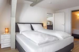 1 dormitorio con cama blanca y almohadas blancas en Gutshaus No4, en Heiligenhafen