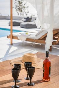 a table with a bottle of wine and three glasses at Oikos Boutique Residences in Plateies