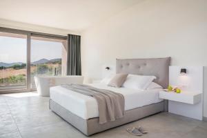 une chambre blanche avec un lit et une grande fenêtre dans l'établissement Oikos Boutique Residences Private Estate, à Plateies