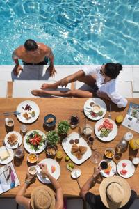 Un groupe de personnes assises autour d'une table avec de la nourriture dans l'établissement Oikos Boutique Residences Private Estate, à Plateies