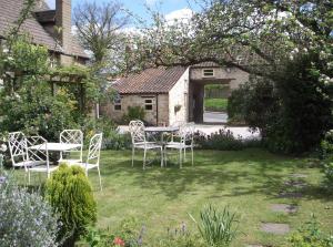a garden with a table and chairs in the yard at Bramwood Cottages in Pickering