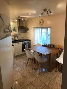 cocina con mesa de madera y sillas blancas en Bottesford Cottage - Leicestershire, en Bottesford