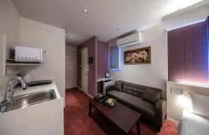 a living room with a couch and a sink at GRAND BASE Okayama Ekimae in Okayama