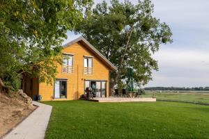 a yellow house on a lawn with a field at Houses with a View#Sauna#Jaccuzi in Gozdowice