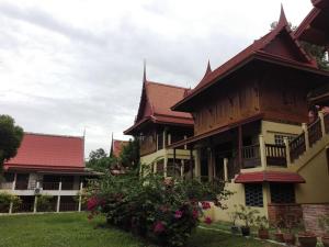 een gebouw met een houten dak en enkele bloemen bij Luang Chumni Village in Phra Nakhon Si Ayutthaya