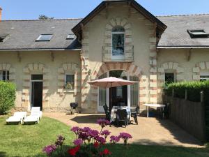 una casa con una mesa y una sombrilla en el patio en Loire Valley Cottages, en Jarzé