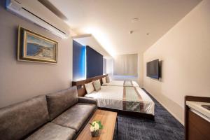 a hotel room with a bed and a couch at GRAND BASE Okayama Ekimae in Okayama