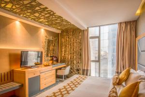 una camera d'albergo con un letto, una scrivania e una televisione di Grand Plaza Hotel - Gulf Riyadh a Riyad