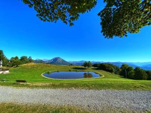 a pond on a hill with mountains in the background at Il Roccolino in Valsecca