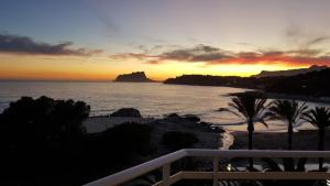 a sunset on the beach with a view of the ocean at Moraira Beach in Moraira