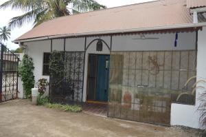 ein weißes Haus mit einem Tor und einer blauen Tür in der Unterkunft Gecko Cottage in Bagamoyo