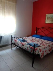 1 dormitorio con 1 cama con pared roja en kola age, en Peschiera del Garda
