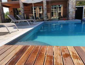 una piscina con terraza de madera y una casa en Modus Aquae, en Brisighella