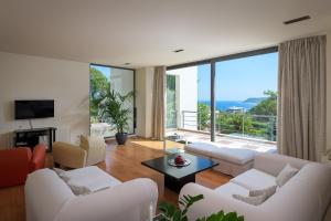 a living room with white furniture and a large window at Ixian Hilltop Villa in Ialysos