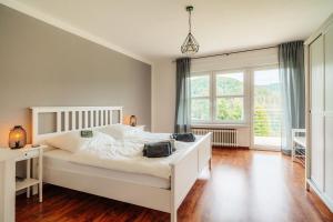 1 dormitorio con cama blanca y ventana grande en FeWoLa en Wieda
