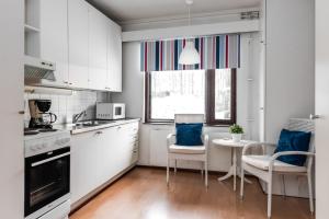 a kitchen with white cabinets and a table and chairs at Hotel Pohjankievari in Kempele