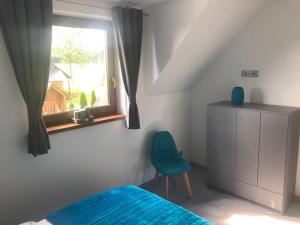 a bedroom with a blue bed and a window at Apartament NATURA in Piekielnik