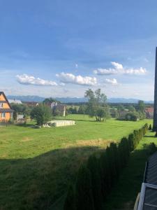 um campo de relva verde com uma casa ao fundo em Apartament NATURA em Piekielnik