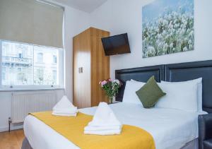 a bedroom with a large white bed with towels at Hyde Park Executive Apartments in London