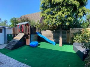 un patio trasero con un parque infantil con un tobogán en Ferienhaus Schaumann, en Ditzum
