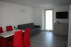 sala de estar con sofá, mesa y sillas rojas en appartamenti i fiori del lago, en Laveno