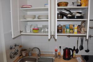 a kitchen with a sink and shelves with dishes at GardenOasisBerlinAirport in Schönefeld