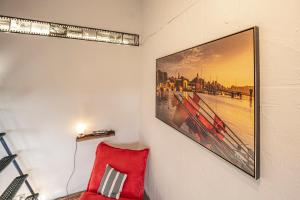 einen roten Stuhl in einem Raum mit einem Bild an der Wand in der Unterkunft Louse Puschen Manufaktur in Kiel