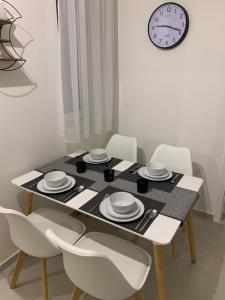 een eettafel met witte stoelen en een klok bij Zenit Apartman in Bükfürdő