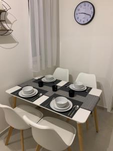 mesa de comedor con sillas blancas y reloj en Zenit Apartman, en Bükfürdő