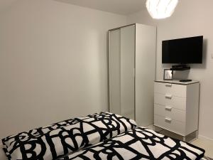 1 dormitorio con 1 cama y vestidor con TV en Zenit Apartman, en Bükfürdő