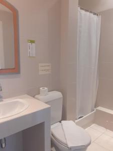 a white bathroom with a toilet and a sink at Hôtel P.L.M. in Cannes