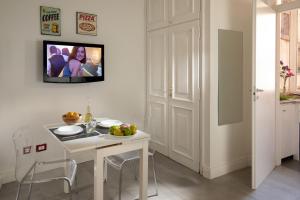 ローマにあるCozy studio Parlamentoの白いテーブルと壁掛けテレビ付きのキッチン
