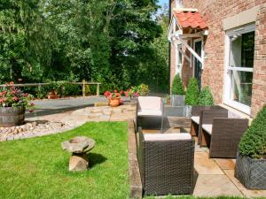 a backyard with wicker chairs and a lawn at Sycamore Cottage in Yarm