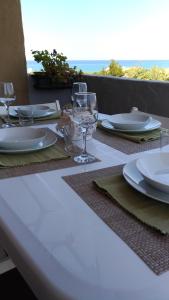 un tavolo con piatti e bicchieri da vino sopra di I Ginepri Holiday Home a Marina di Sorso