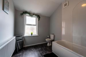 a bathroom with a tub and a toilet and a window at 3 Bedroom Hull Sleeps 6 Glam Contractor & Leisure & Families Close to Clough Rd in Hull +10 photos