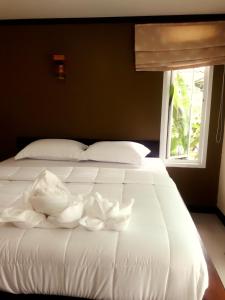 uma cama branca com lençóis brancos e uma janela em Lung Pod 9 resort em Chumphon
