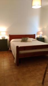 een slaapkamer met een bed met 2 nachtkastjes en 2 lampen bij I Ginepri Holiday Home in Marina di Sorso