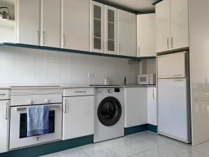 a kitchen with white cabinets and a washer and dryer at Duplex a 25 metros de la playa in Somo