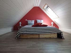 um quarto com uma cama com uma parede vermelha em TY KASTELL PAOL em Saint-Pol-de-Léon