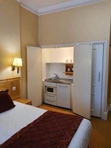 a hotel room with a bed and a kitchen at Grange Portland Hotel in London